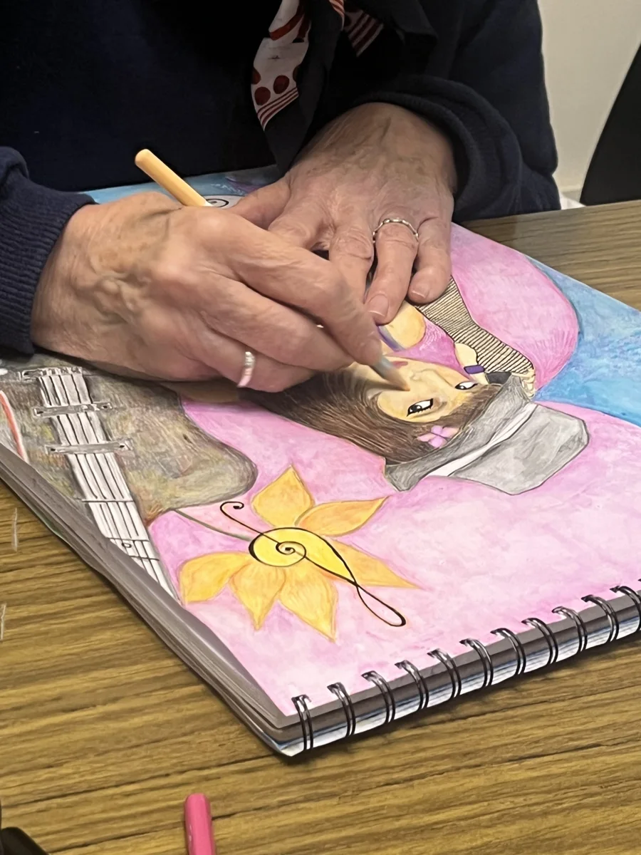 Una estudiante trabaja con lápices de colores en su ilustración.
